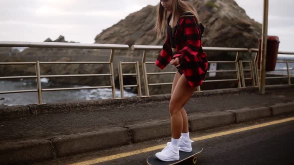 Young Pretty Beautiful Brunette Hipster Woman in Plaid Coat Having Fun Riding Skateboard Longboard