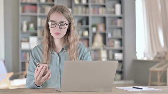 Portrait of Cheerful Woman Using Smartphone and Working on Laptop