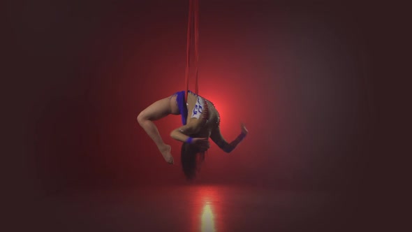 Beautiful Aerialist Girl Doing Acrobatic and Flexible Tricks on Red Aerial Silks Tissues on Red