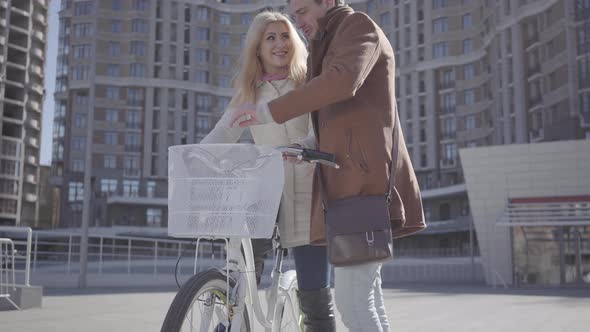 Handsome Man in Brown Coat Teaching His Girlfriend To Ride the Bicycle in the City, Both People