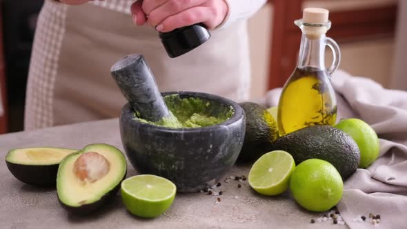 Making Guacamole Sauce Woman Adding Pepper and Spices to Mashed Avocado in a Marble Mortar with