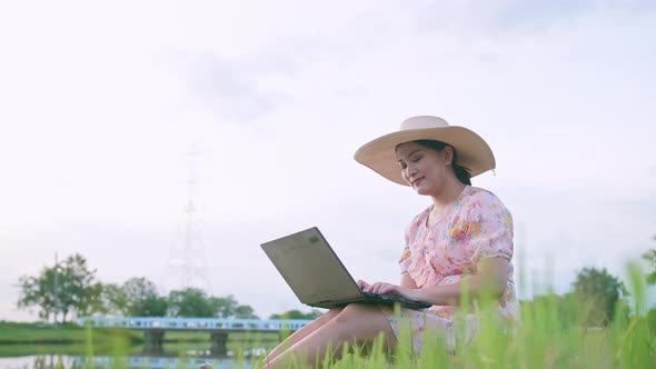 Freelance Asian woman using a notebook in the external nature area.