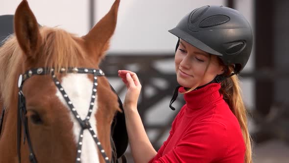 Beautiful Girl in Helmet Stroking a Horse Outdoors