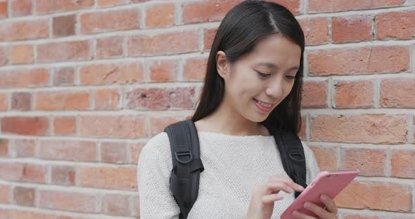Woman use of smart phone over red brick wall