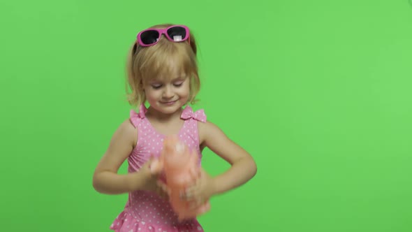 Child in Pink Swimsuit Playing with a Toy Pig. Chroma Key