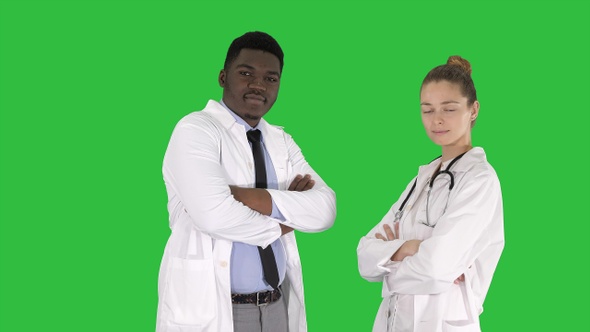 Woman and man doctors with crossed arms on a Green Screen