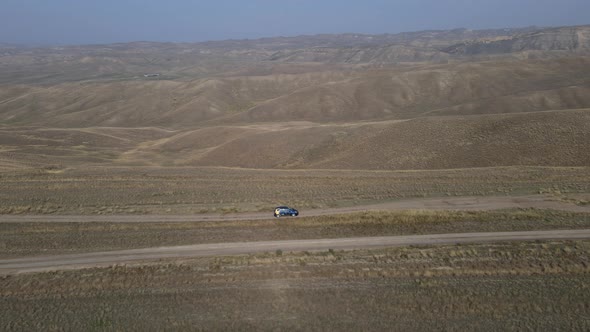 Aerial View of a Car Driving on a Road in a Desert in Gareji Ridge Georgia