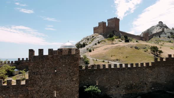 Ancient Medieval Genoese Fortress Tower on Mountain Range Rocks Above Sea Aerial View From Drone to