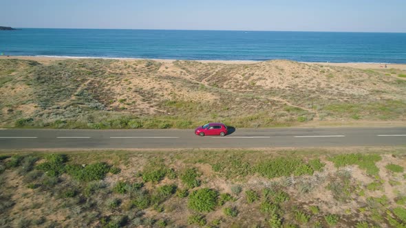 Red Car Driving on a Coastal Road Along the Black Sea