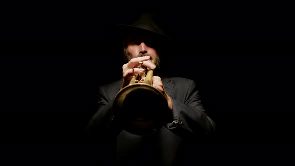 Male Musician Plays Trumpet on Dark Background Illuminated By Spotlight Front View