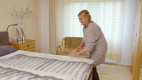 Older woman making her bed and looks relaxed