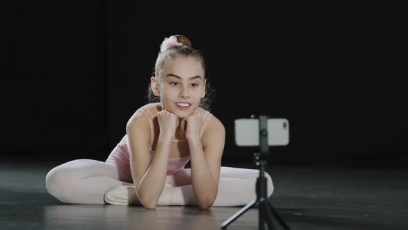 Young Teen Girl Child Teenager Ballerina Gymnast Dancer Sitting on Floor Recording Vlog Waving Hello