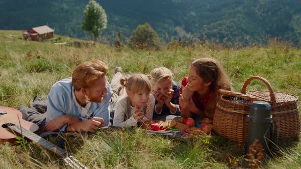 Friendly Family Enjoy Picnic on Grass Mountain Hill