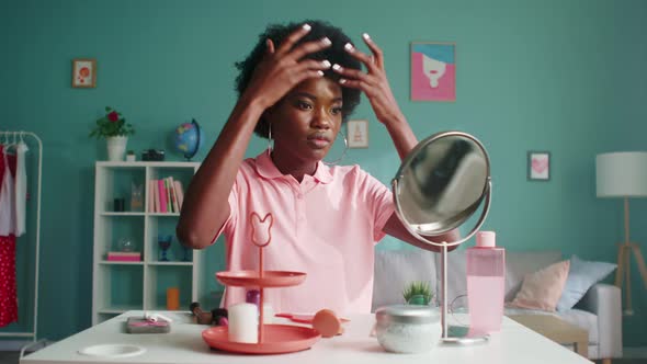 Young Woman Is Looking in Mirror Making Hairstyle