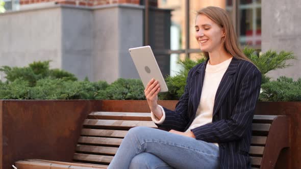 Video Chat on Tablet By Business Woman Sitting Outside Office