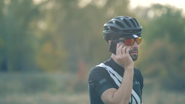 Cyclist In Sunglasses Talking On Mobile Phone. Cyclist On Sportswear, Sunglasses And Helmet Resting.