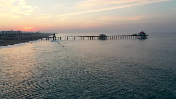 A stunning 4k parallax circling of the pier in Surf City California USA at sunrise as tourists and p