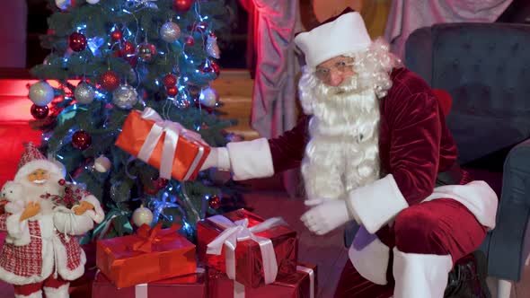 Santa putting gifts under Christmas tree.