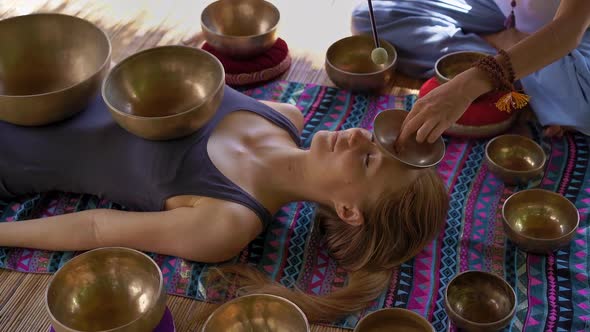 Superslowmotion Shot of a Woman Master of Asian Sacred Medicine Performs Tibetan Bowls Healing