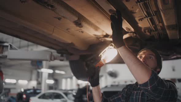 Male Auto Mechanic Checking Undercarriage of Car