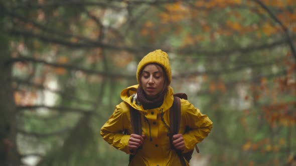 Close Up Portrait of Pretty Young Woman Hiker with Backpack Wearing Bright Yellow Raincoat and