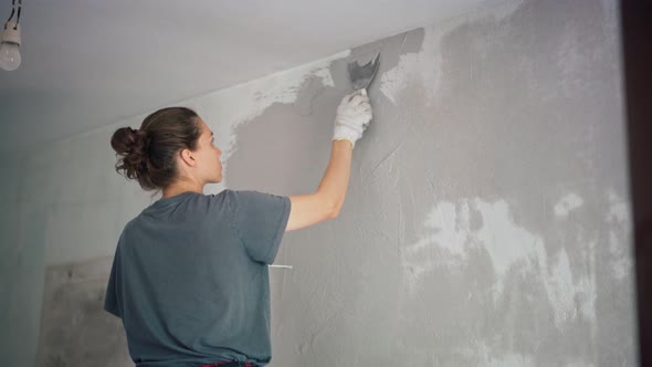 A Professional Repairwoman Puts a Plaster on the Wall with a Spatula