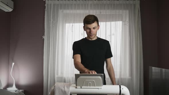 Man is training on treadmill, touching tablet screen, using new technology