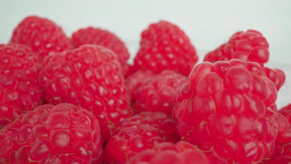 Container with Raspberries Against White Wall Macro