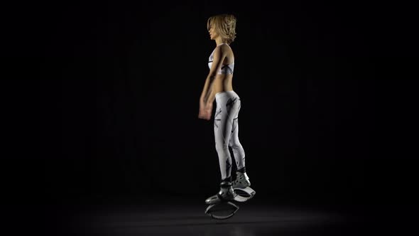 Athletic Girl Jumping in Kangoo Shoes Among Spotlights in Smoke on Black Background at Studio