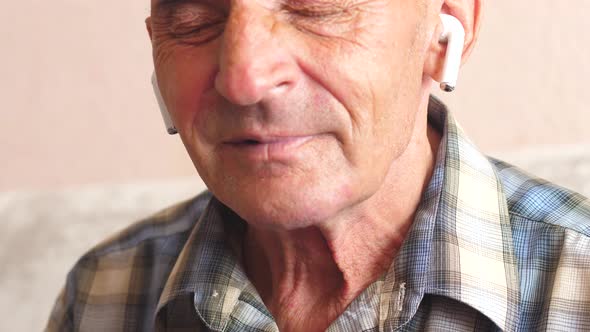 portrait of a cheerful Caucasian pensioner over 70 years old in airpods listening to music with his 