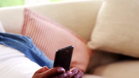 Man using mobile phone on sofa in living room