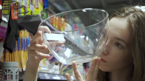 A Young Woman in a Store Choosing Dishes