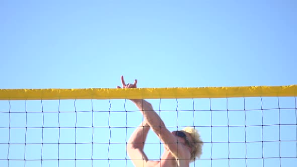 A man spiking a beach volleyball