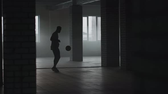 A Man Kick the Football Into a Wall in an Underground Parking Lot in the Sunlight in Slow Motion