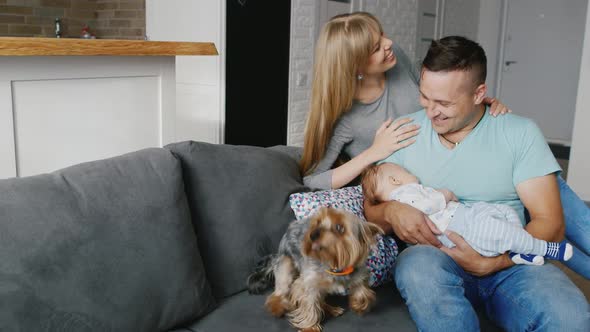 A Young Couple Laughing and Smiling Cheerfully. Dad Holds Baby in Her Arms, They Are Happy