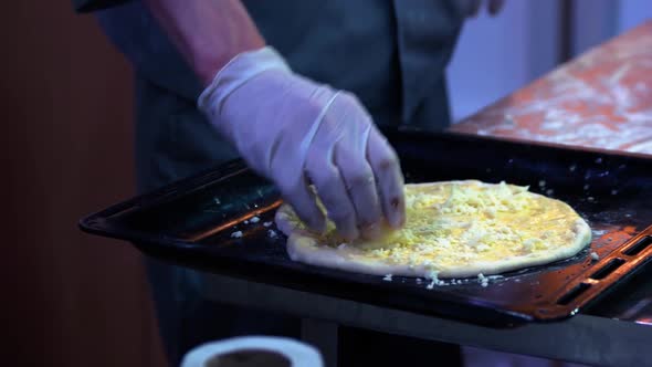 Closeup Cooks Hands Adding Up Shredded Cheese to a Pizza Dough