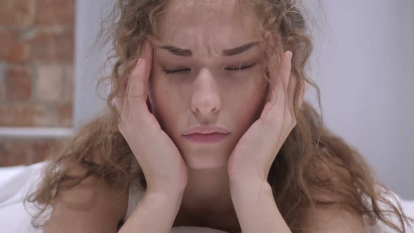 Beautiful Young Female with Stress and Headache Lying in Bed