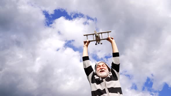 Happy Greybeard Man Pretend Flying on Wooden Plane in Sky Travel