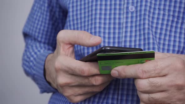 Closeup of Man Hands Holding Credit Card and Using Smartphone
