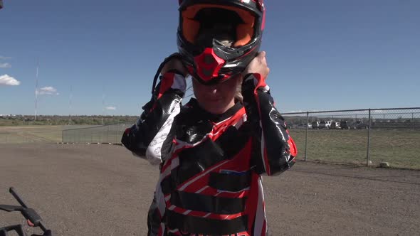 A young woman bmx rider putting on helmet.