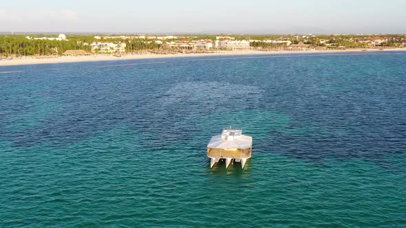 Trimaran party boat stationed near resort beach at Punta Cana Dominican Republic, Aerial orbit left