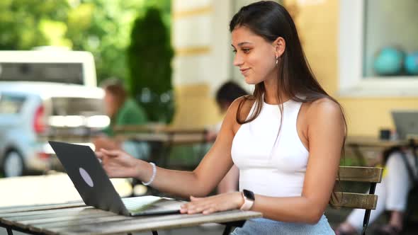 Beautiful Woman Working on Laptop at Outdoors Cafe