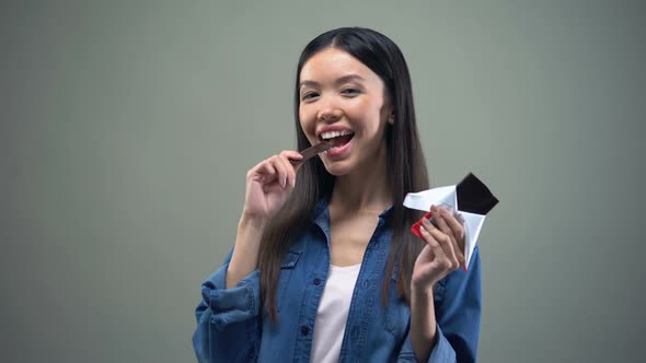 Attractive Asian Girl Smiling on Camera Eating Dark Chocolate, Advertisement