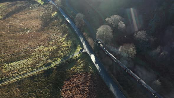 Aerial view of a steam train leaving a little town station in Wales and trave