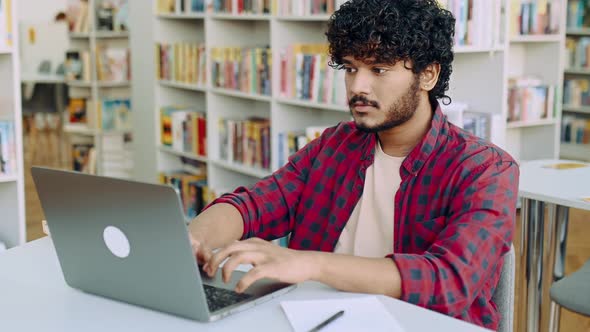 Clever Confident Positive Arabian or Indian Male Student Stylishly Dressed Sit at Table with Laptop