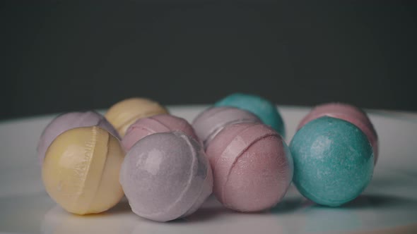 Bath Bombs in Different Colors Spin Against a Black Background