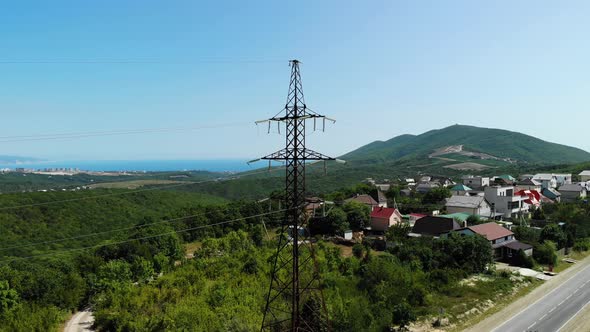 Aerial Shot of an Electric Tower in the Countryside Among Green Mountains. The Blue Sky Over the