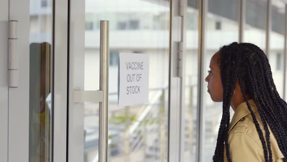 African Woman Read Vaccine Out of Stock Sign on Hospital Glass Door