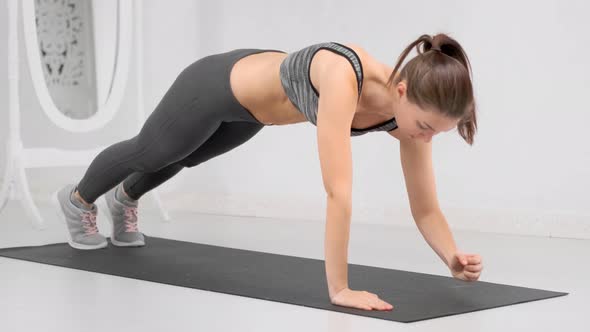 Athletic Woman with Perfect Slim Body Making Abs Exercising on Mat at White Fitness Studio