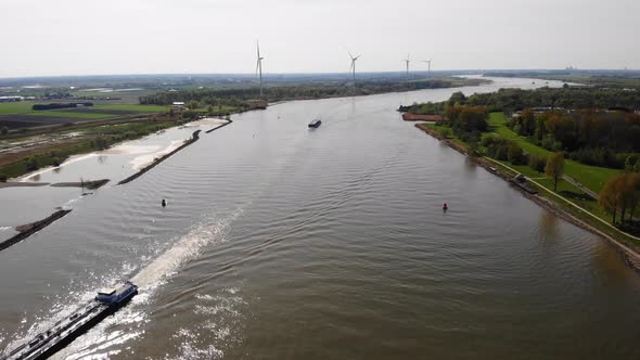 Aerial View Over Oude Maas With Ships Navigating Past Still Wind Turbine On Riverside Bank On 18 Apr